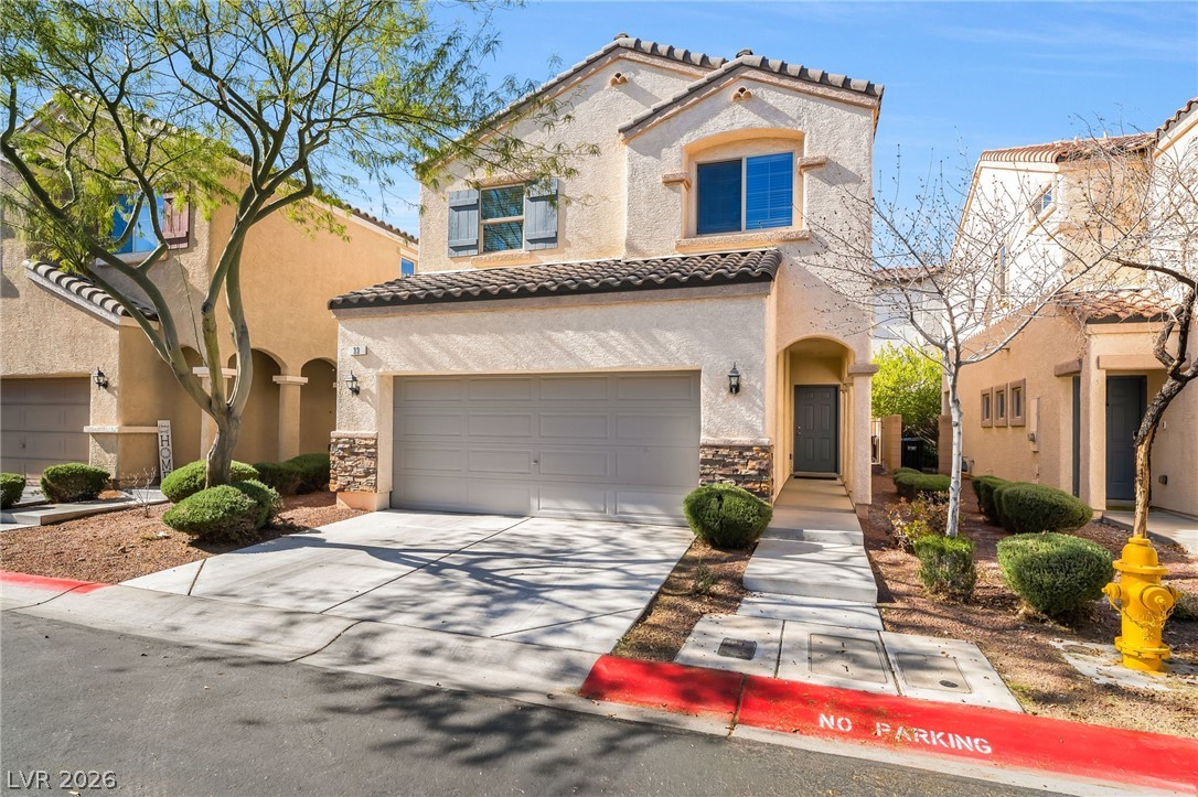 Mediterranean / spanish-style house featuring a tiled roof, concrete driveway, stucco siding, and stone siding