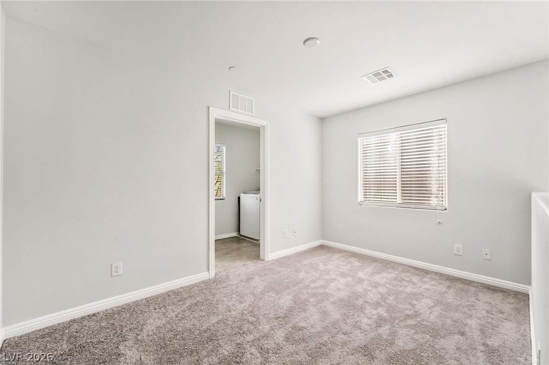 33 Jasmine Point Street Henderson, NV 89074 - Photo 14 of 36 Empty room featuring light colored carpet, healthy amount of natural light, and washer / dryer