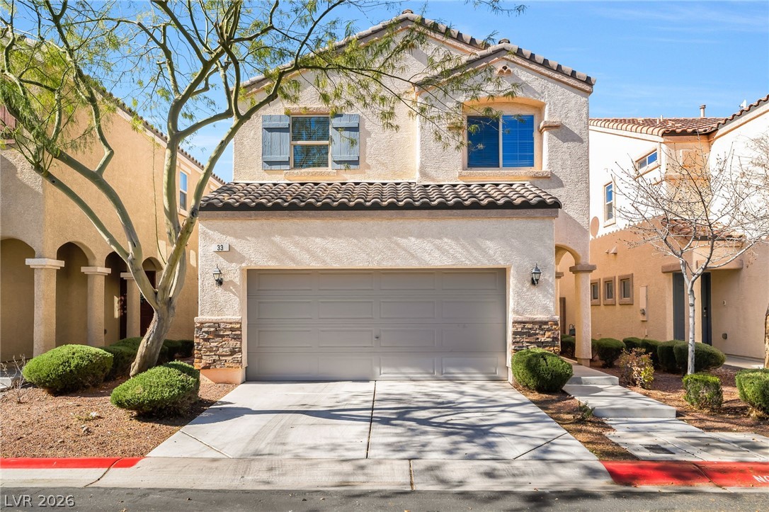 33 Jasmine Point Street Henderson, NV 89074 - Photo 2 of 36 Mediterranean / spanish house with stone siding, a garage, concrete driveway, and a tiled roof