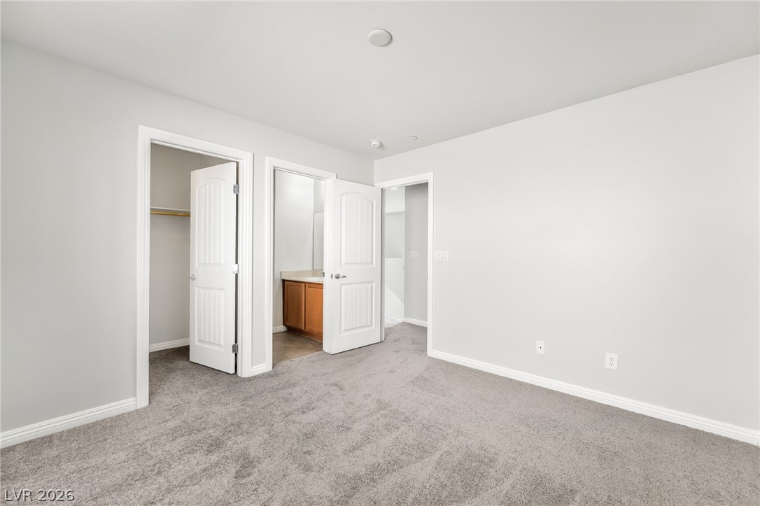 33 Jasmine Point Street Henderson, NV 89074 - Photo 25 of 36 Unfurnished bedroom featuring light colored carpet, a walk in closet, and ensuite bathroom