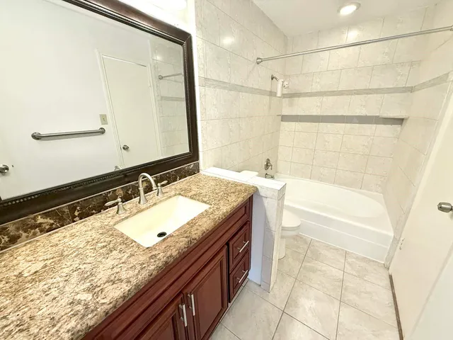 a bathroom with a granite countertop sink and a bathtub