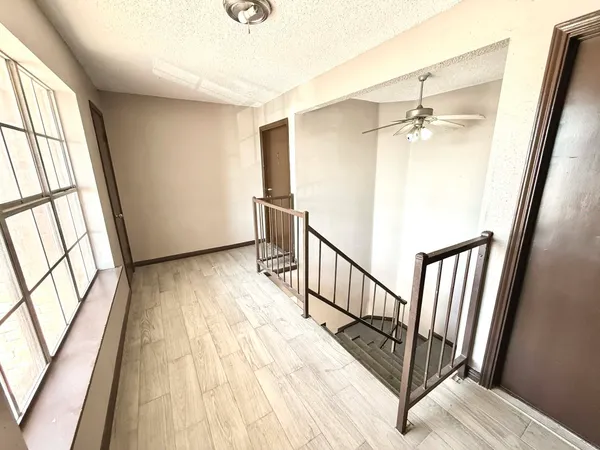 a view of a hallway with wooden floor and staircase