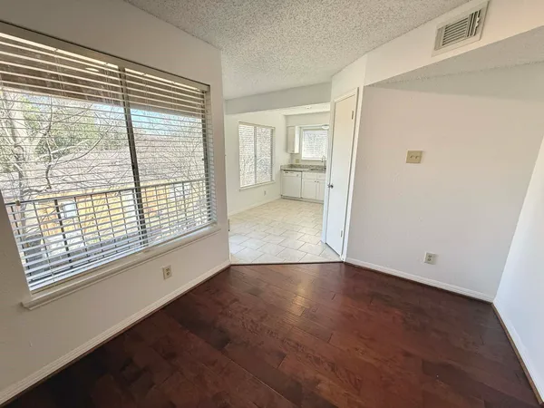 a view of an empty room with a window and wooden floor