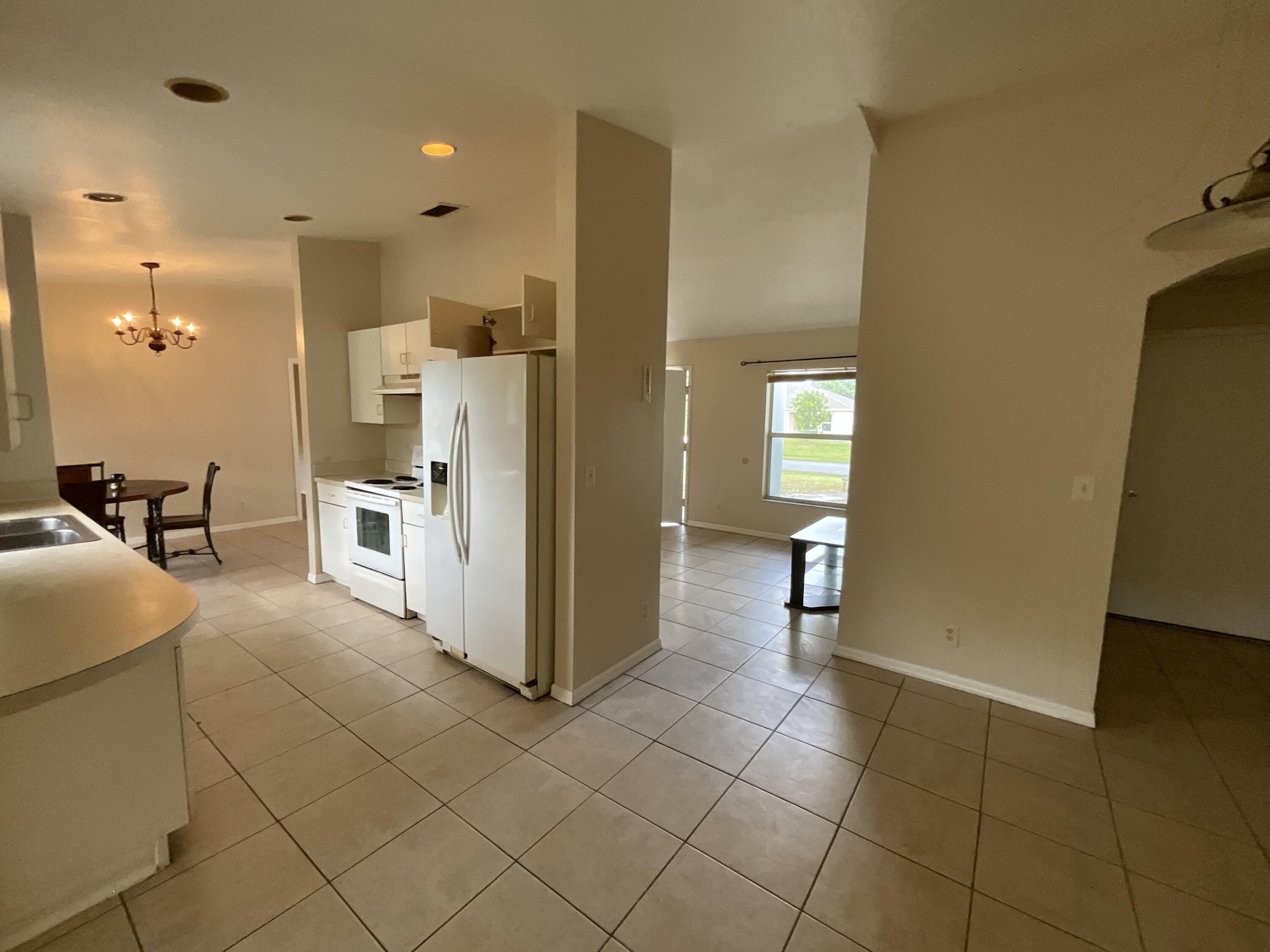 1002 Southwest Romaine Lane Port St. Lucie, FL 34953 - Photo 11 of 26 a kitchen with stainless steel appliances kitchen island granite countertop a refrigerator and a sink