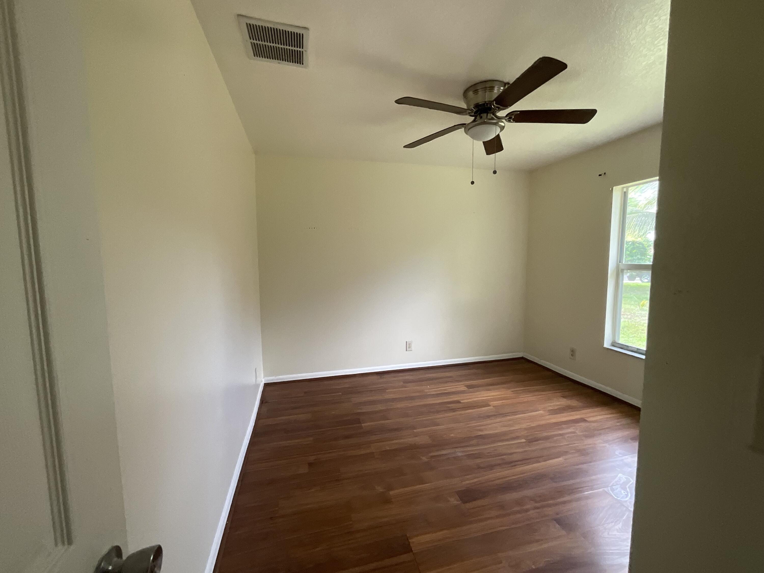 1002 Southwest Romaine Lane Port St. Lucie, FL 34953 - Photo 13 of 26 a view of a room with wooden floor a ceiling fan