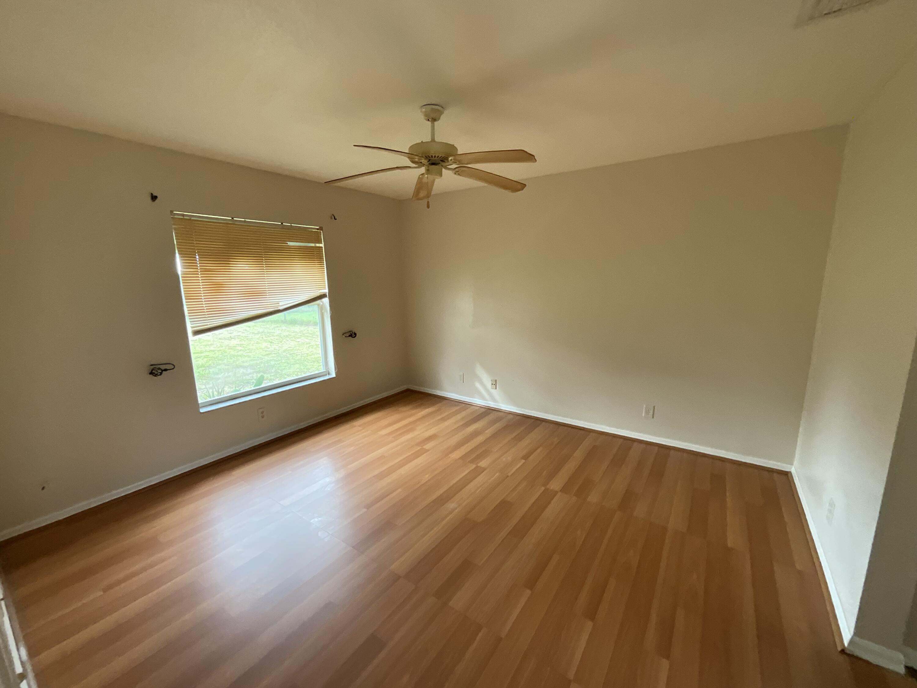 1002 Southwest Romaine Lane Port St. Lucie, FL 34953 - Photo 20 of 26 an empty room with wooden floor fan and windows