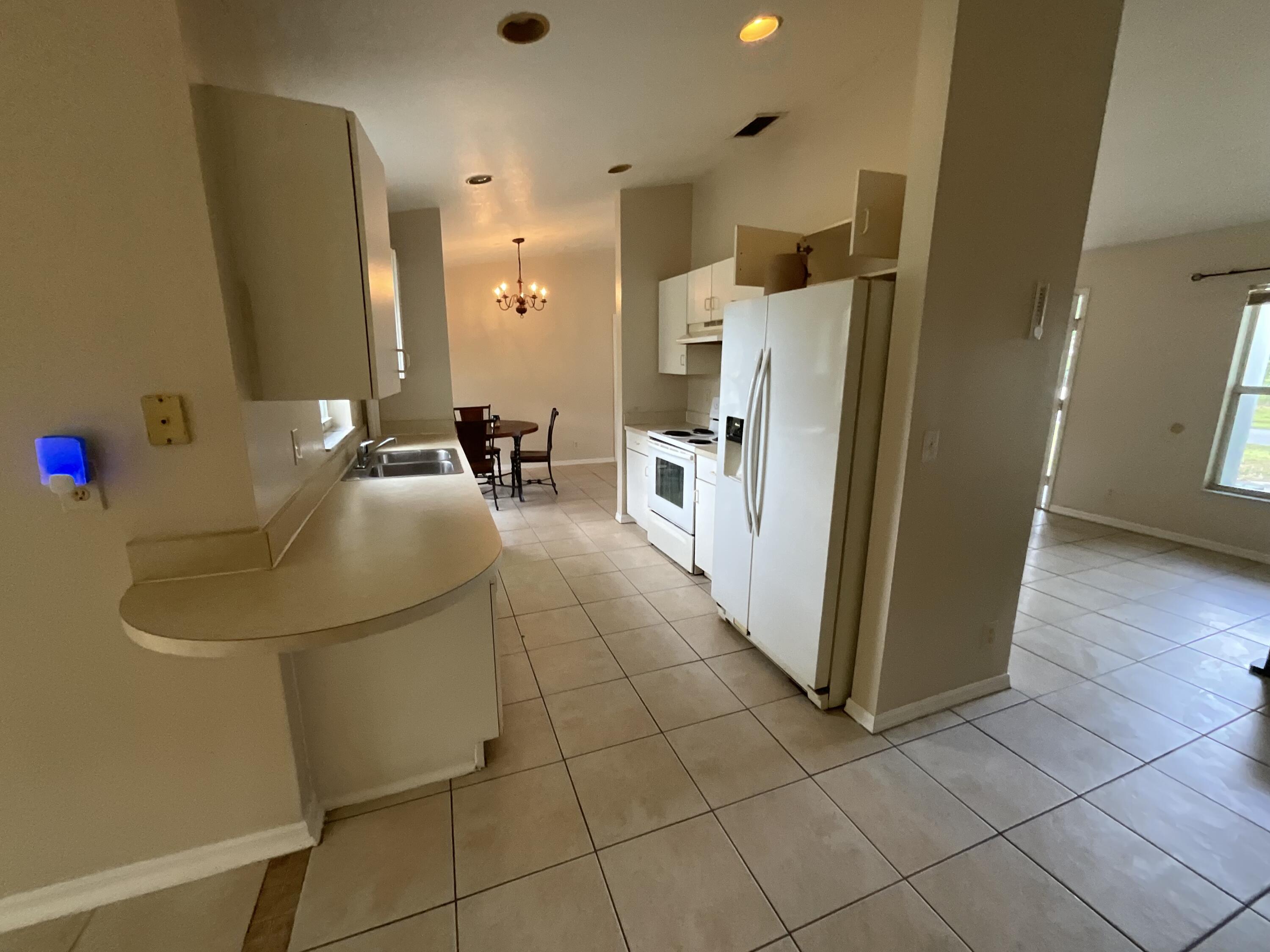 1002 Southwest Romaine Lane Port St. Lucie, FL 34953 - Photo 8 of 26 a kitchen with a sink a refrigerator and cabinets