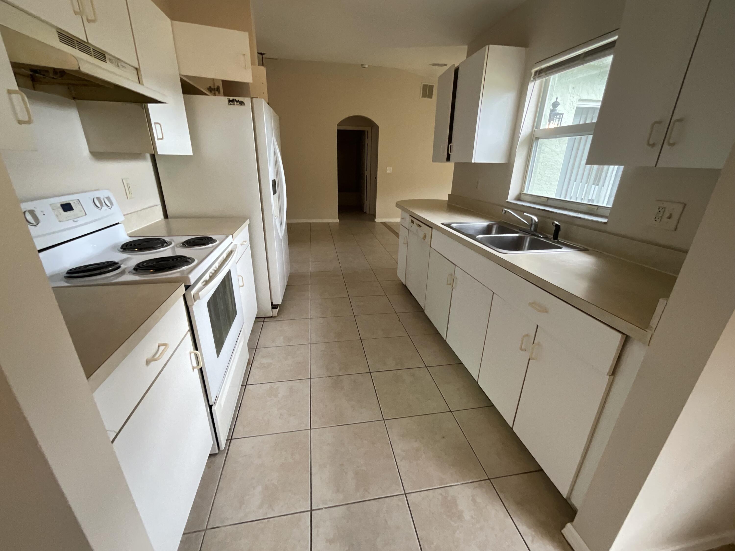 1002 Southwest Romaine Lane Port St. Lucie, FL 34953 - Photo 9 of 26 a kitchen with refrigerator a stove a washer and dryer