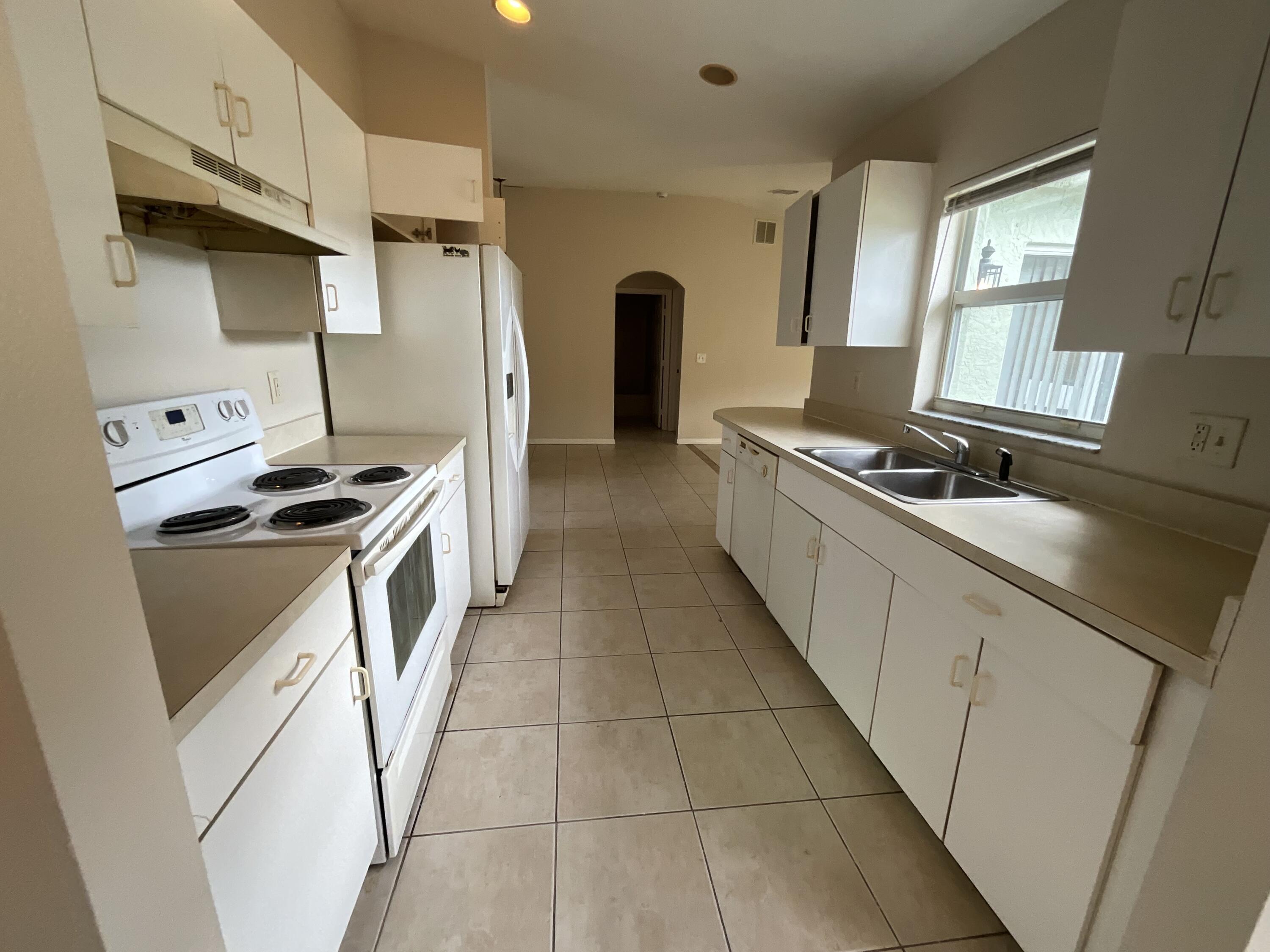 1002 Southwest Romaine Lane Port St. Lucie, FL 34953 - Photo 10 of 26 a kitchen with stainless steel appliances a sink stove and refrigerator