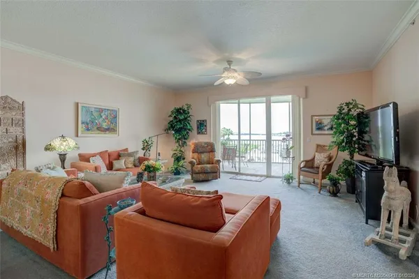 a living room with furniture a flat screen tv and a floor to ceiling window