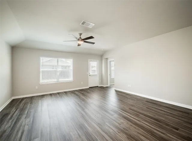 a view of an empty room with wooden floor and a window
