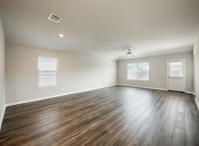 an empty room with wooden floor and windows