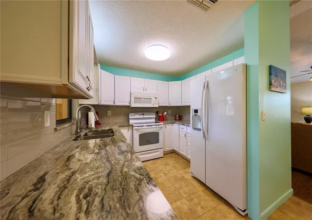 a kitchen with granite countertop a refrigerator and a stove top oven