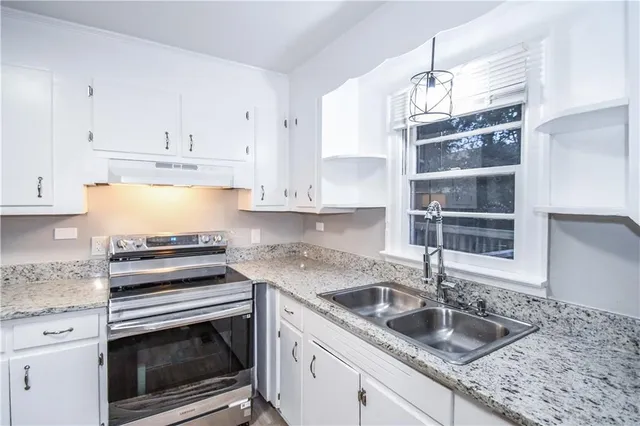 a kitchen with granite countertop a sink stainless steel appliances and cabinets