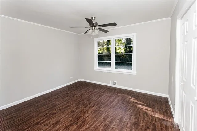 a view of an empty room with wooden floor and a window
