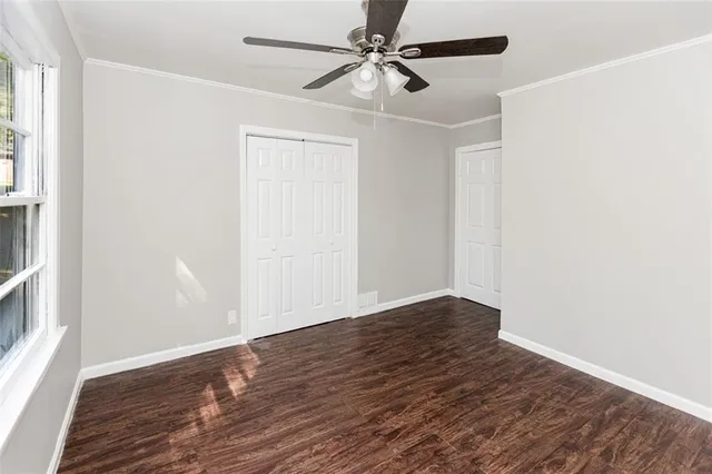 an empty room with wooden floor ceiling fan and windows