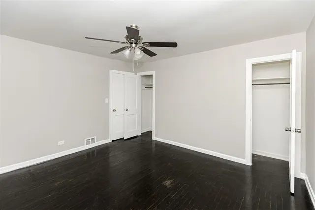 an empty room with wooden floor closet and fan