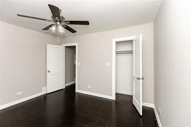 an empty room with wooden floor closet and windows