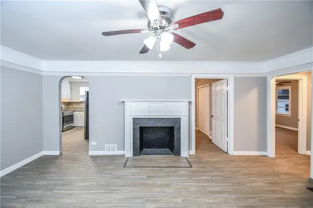 a view of an empty room with wooden floor fireplace and a window