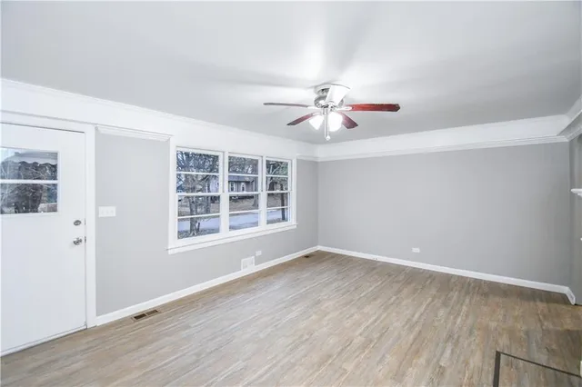 a view of an empty room with a window and wooden floor