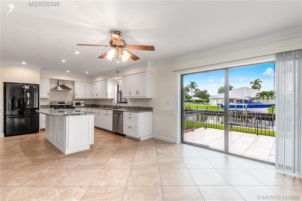 1239 Southwest Dyer Point Road Palm City, FL 34990 - Photo 11 of 34 a kitchen with stainless steel appliances kitchen island granite countertop a refrigerator a sink a stove and white cabinets