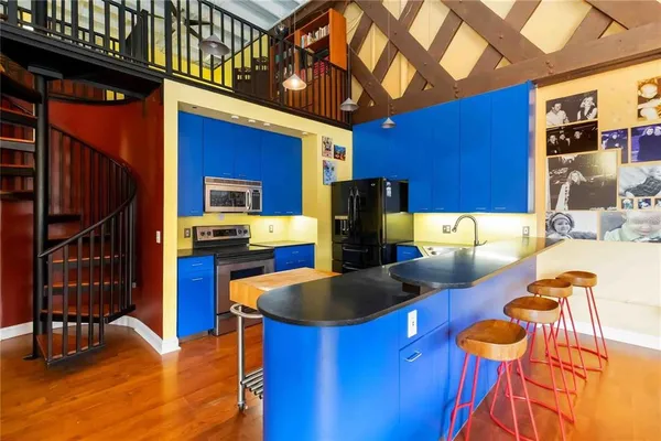 a kitchen with stainless steel appliances kitchen island granite countertop a table chairs in it and a wooden floor