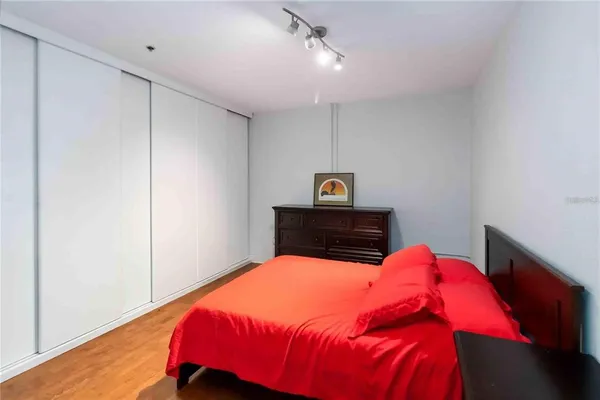 a bedroom with a bed and a dresser with wooden floor