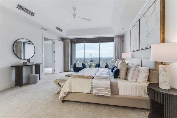 a bedroom with a bed a mirror and a large window with outer view