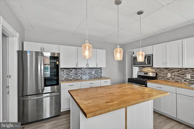 a kitchen with kitchen island a counter top space a sink stainless steel appliances and cabinets