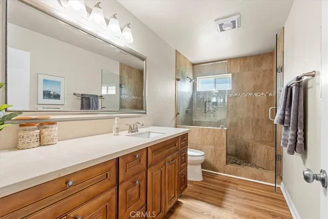 a bathroom with a double vanity sink a toilet a mirror and shower