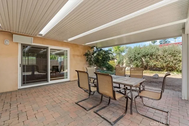 a view of a patio with table and chairs and floor to ceiling window