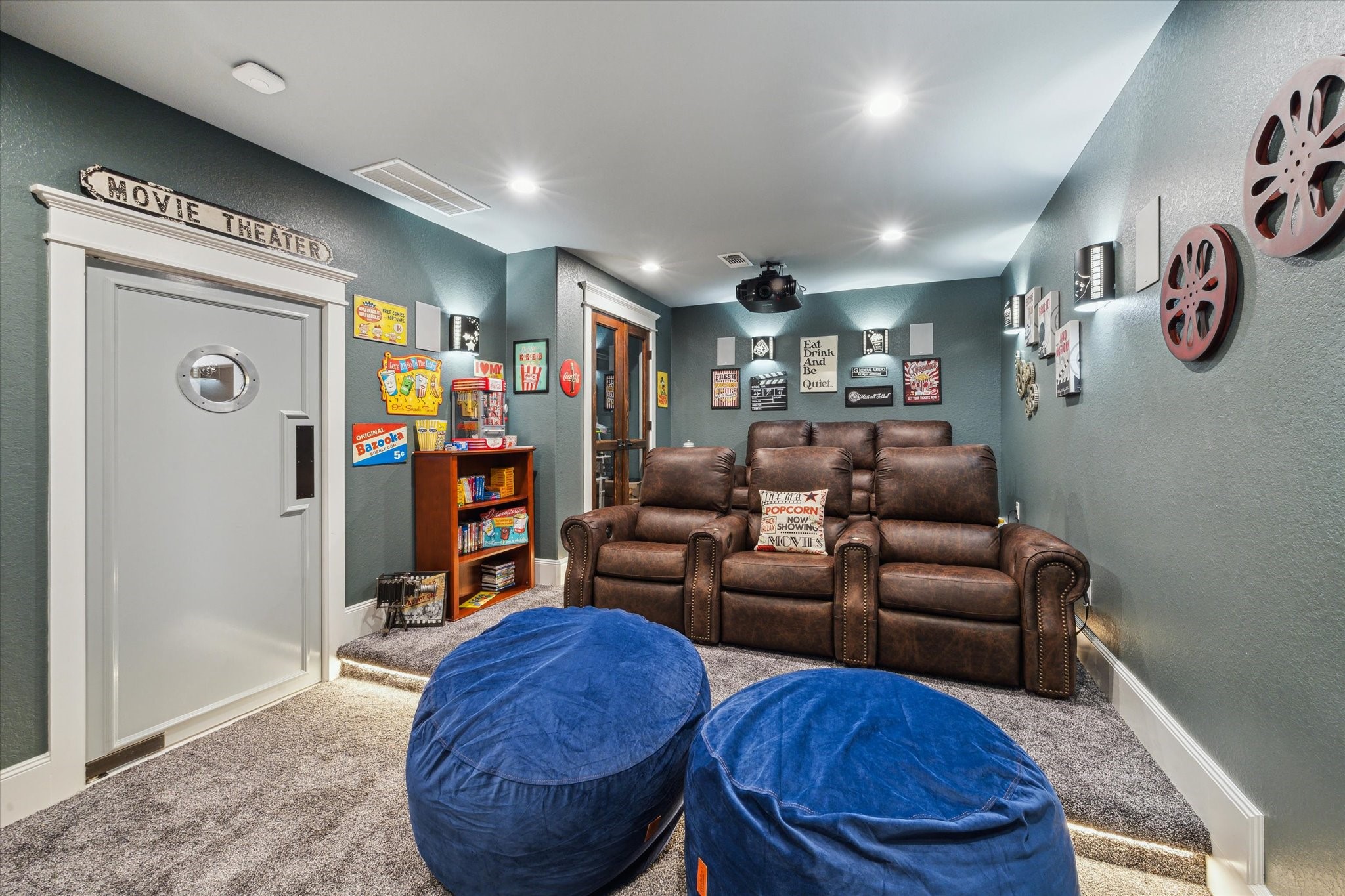 1255 Bronco Trail Angleton, TX 77515 - Photo 28 of 50 This dedicated movie room is designed for the ultimate cinematic experience. The movie-style swinging door with a window and a cinema marquee outside sets the stage for what’s inside. Inside, plush carpet underfoot, custom lighting (including a built-in on-lighting system), and two elevated seating platforms ensure the perfect view for everyone. A glass-doored mechanical closet keeps everything organized, while the projector TV and surround sound system create the perfect environment for movie nights