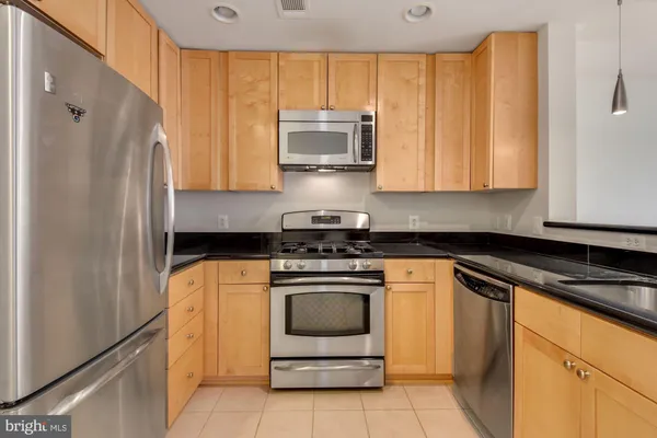 a kitchen with stainless steel appliances granite countertop a stove a refrigerator and a microwave