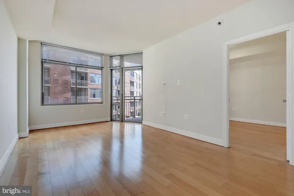 a view of an empty room with a window and wooden floor