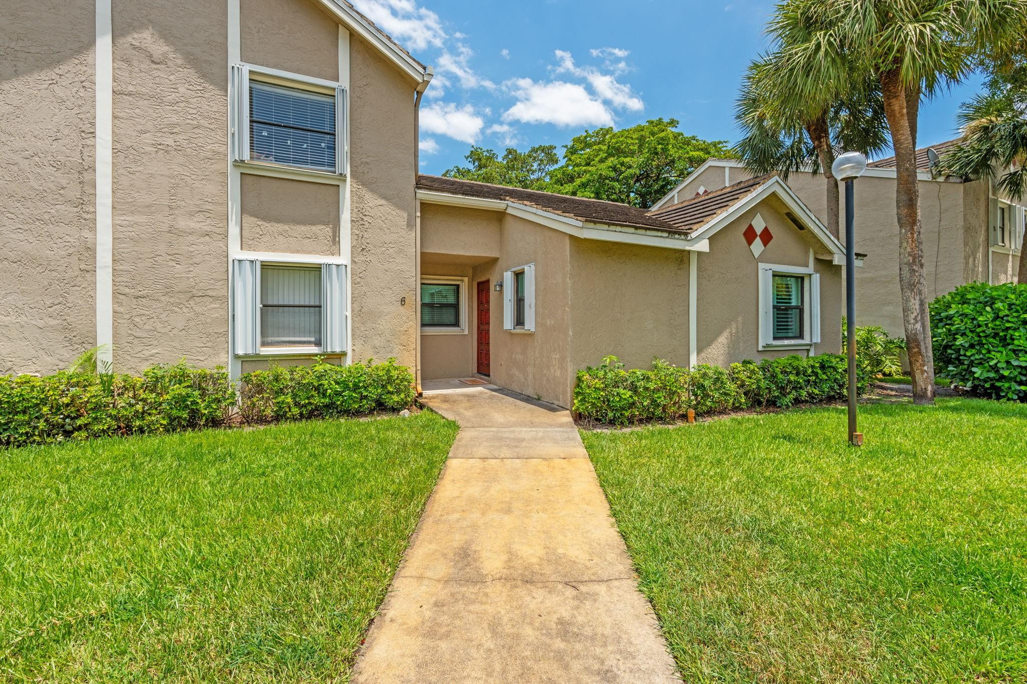 9601 Riverside Drive, Unit A6 Coral Springs, FL 33071 - Photo 22 of 25 a front view of a house with a yard and potted plants