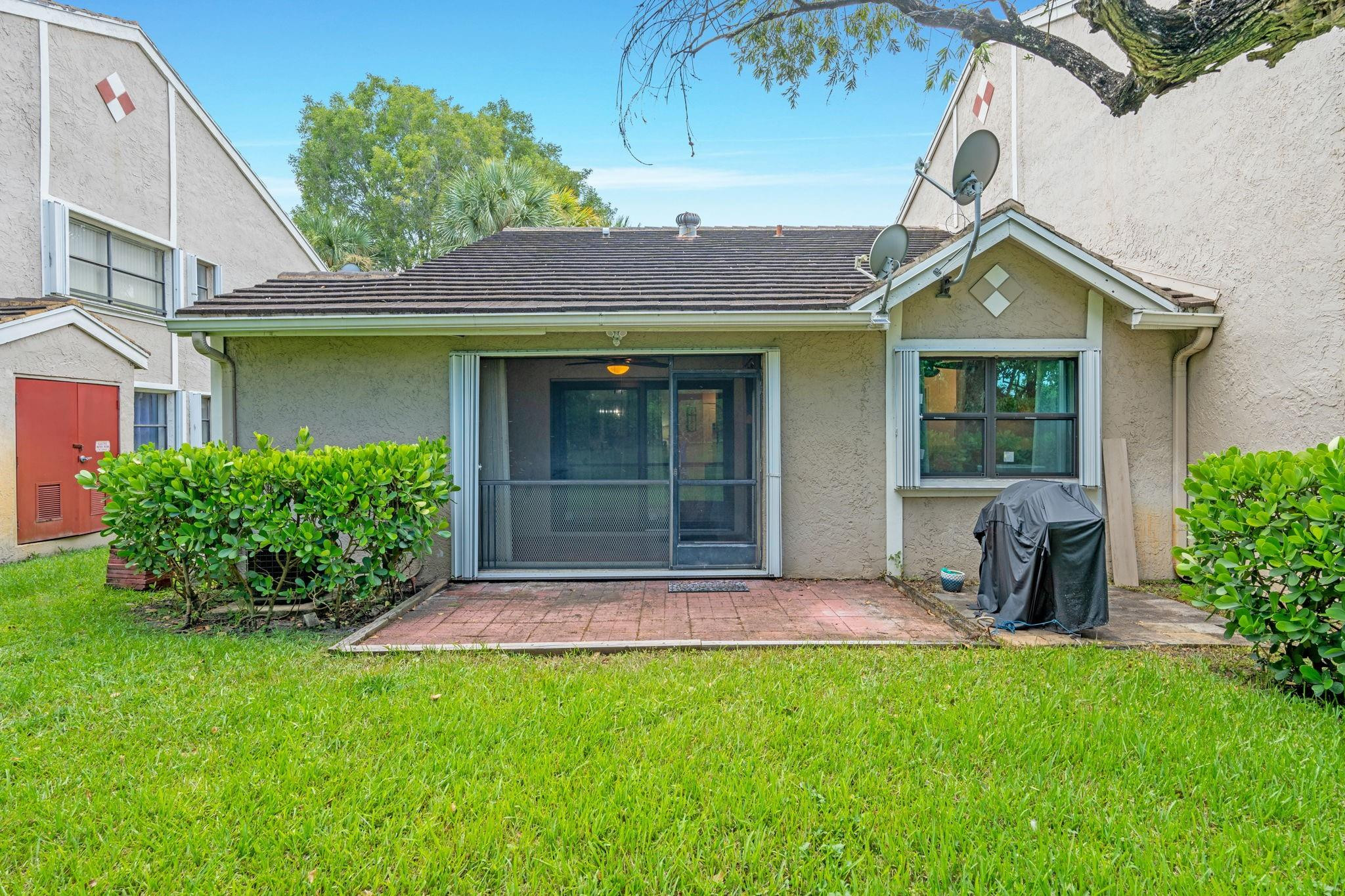 9601 Riverside Drive, Unit A6 Coral Springs, FL 33071 - Photo 23 of 25 a front view of a house with a yard and potted plants