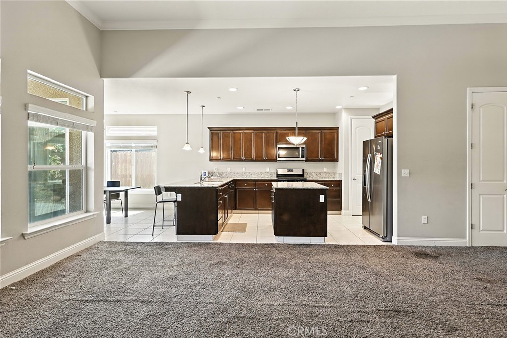 453 Glendon Place Merced, CA 95348 - Photo 15 of 40 a living room with stainless steel appliances kitchen island granite countertop a stove a refrigerator a sink a dining table and chairs