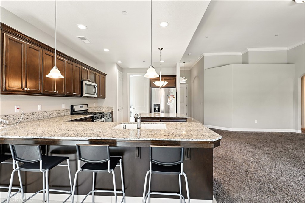 453 Glendon Place Merced, CA 95348 - Photo 18 of 40 a kitchen with granite countertop a table chairs microwave and cabinets