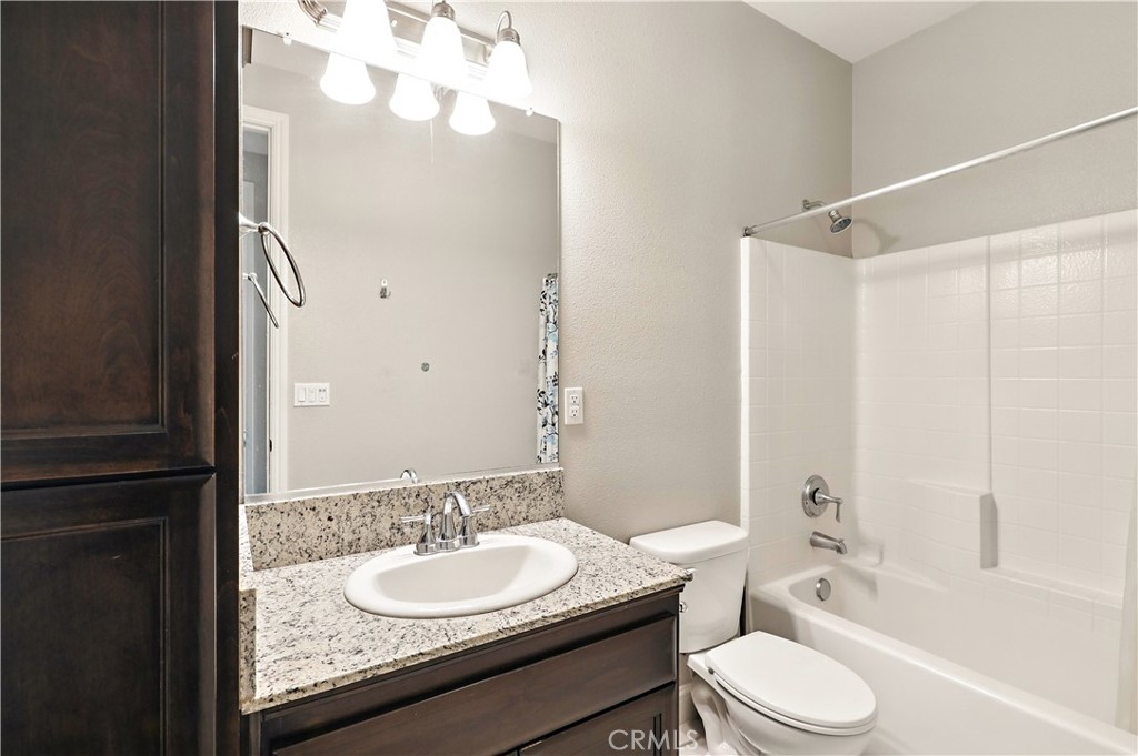 453 Glendon Place Merced, CA 95348 - Photo 29 of 40 a bathroom with a granite countertop sink toilet a mirror and shower