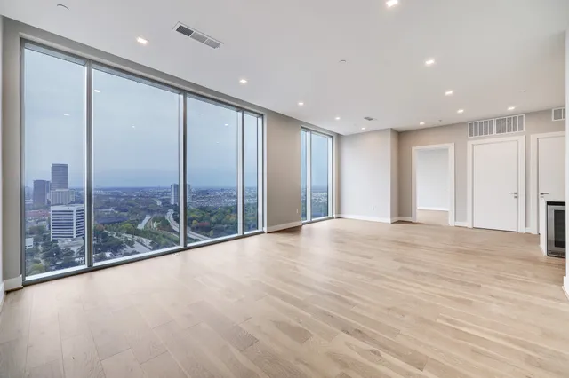 a view of an empty room with wooden floor and glass door