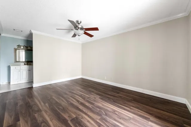 a view of empty room with wooden floor and kitchen view