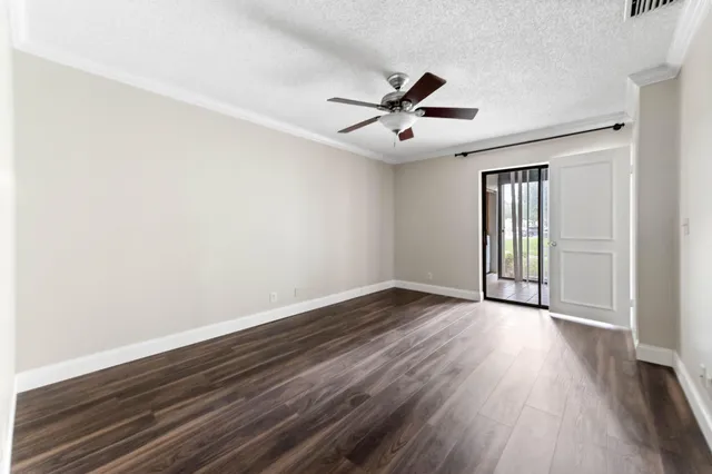 an empty room with wooden floor fan and windows