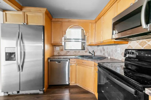 a kitchen with granite countertop a sink stainless steel appliances and cabinets