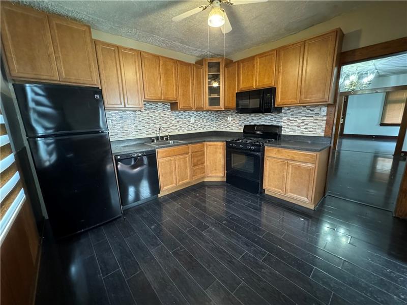 1012 11th Street McKees Rocks, PA 15136 - Photo 13 of 50 a kitchen with granite countertop wooden floors stainless steel appliances and a counter space