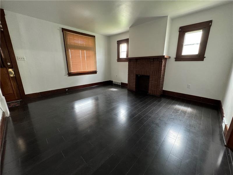 1012 11th Street McKees Rocks, PA 15136 - Photo 6 of 50 an empty room with wooden floor fireplace and windows