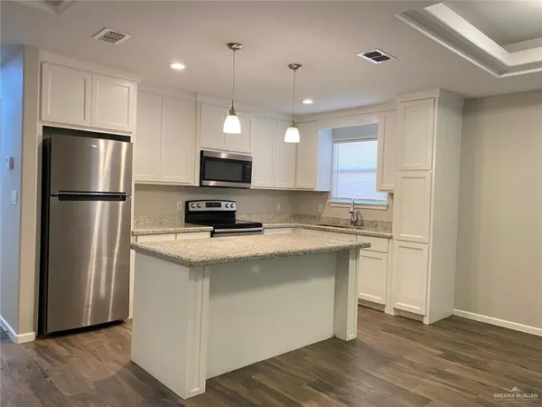 a kitchen with a refrigerator a microwave oven a sink and dishwasher with wooden floor