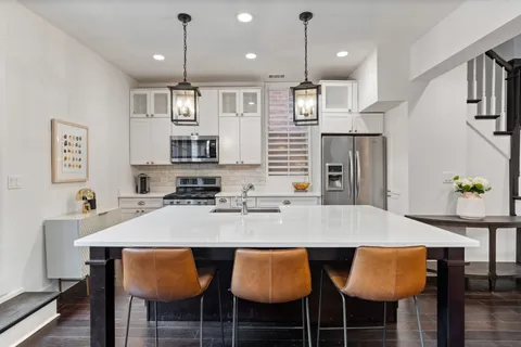 a kitchen with stainless steel appliances granite countertop a table chairs stove and refrigerator