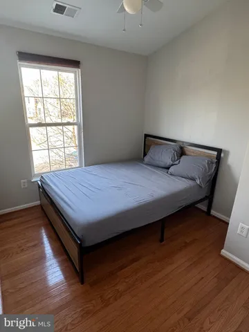 a bedroom with a bed wooden floor and window
