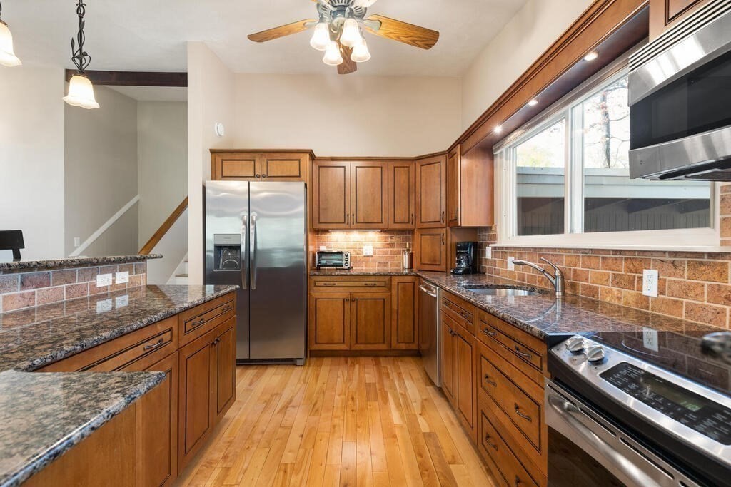 2 Peacock Farm Road Lexington, MA 02421 - Photo 12 of 30 a kitchen with stainless steel appliances granite countertop a refrigerator a sink dishwasher a stove and white countertops with wooden floor