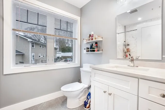 a bathroom with a granite countertop sink mirror vanity and toilet